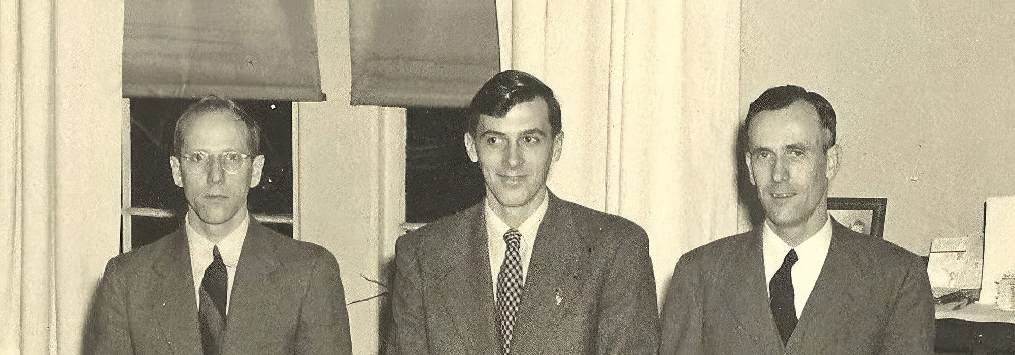 A vintage black-and-white photo of three men in suits, cropped wide, from a 1950s family portrait